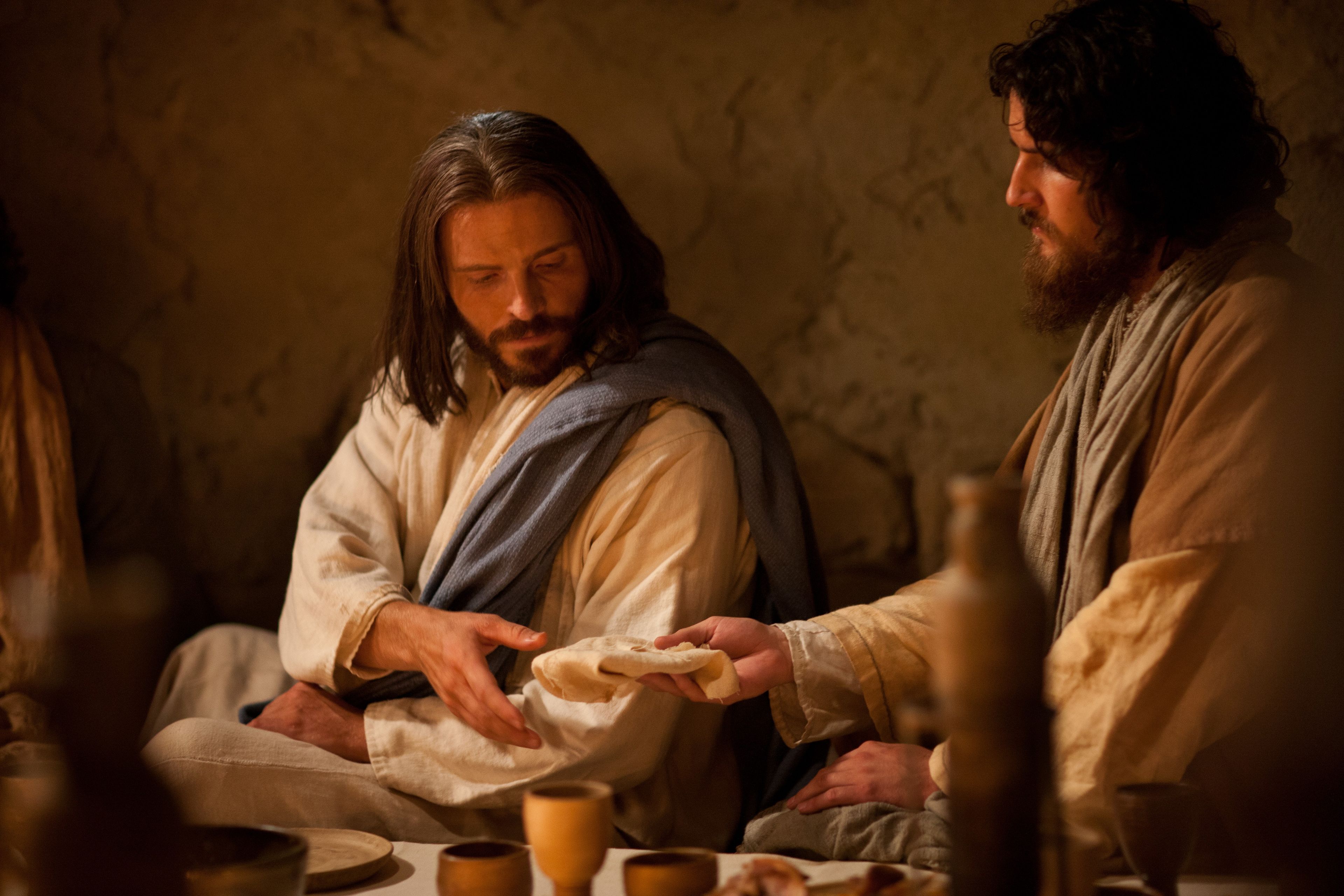 Jesus passing bread to James at the Last Supper.
