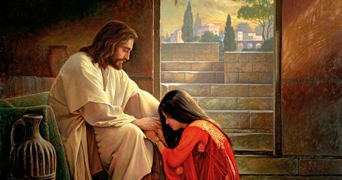 kvinne som kneler ved Jesu føtter