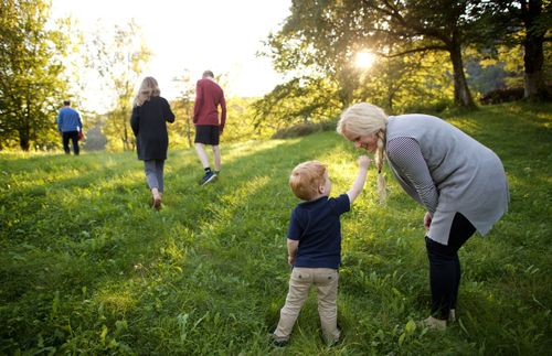 little boy reaching out to his mother as other family memebers walk ahead