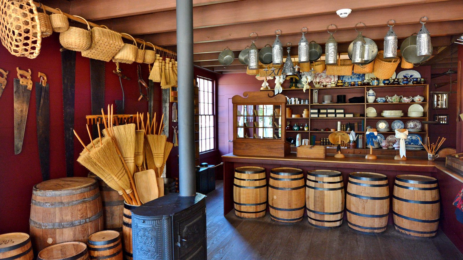 A small wooden store filled with goods from the pioneer era, such as barrels, brooms, saws, pots, and pans.