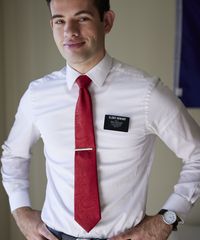 A missionary models appropriate shirts and ties and he smiles and talks to someone off camera.