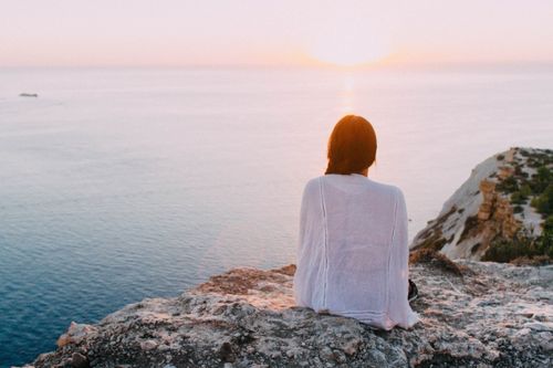 woman sitting on a rock near water