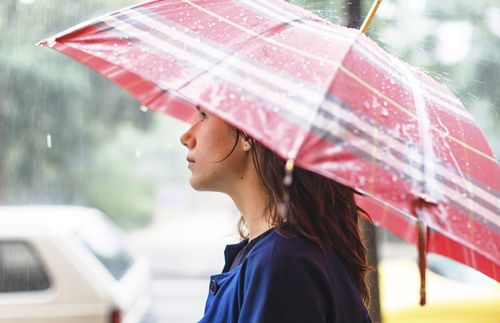 young woman under umbrella in rain