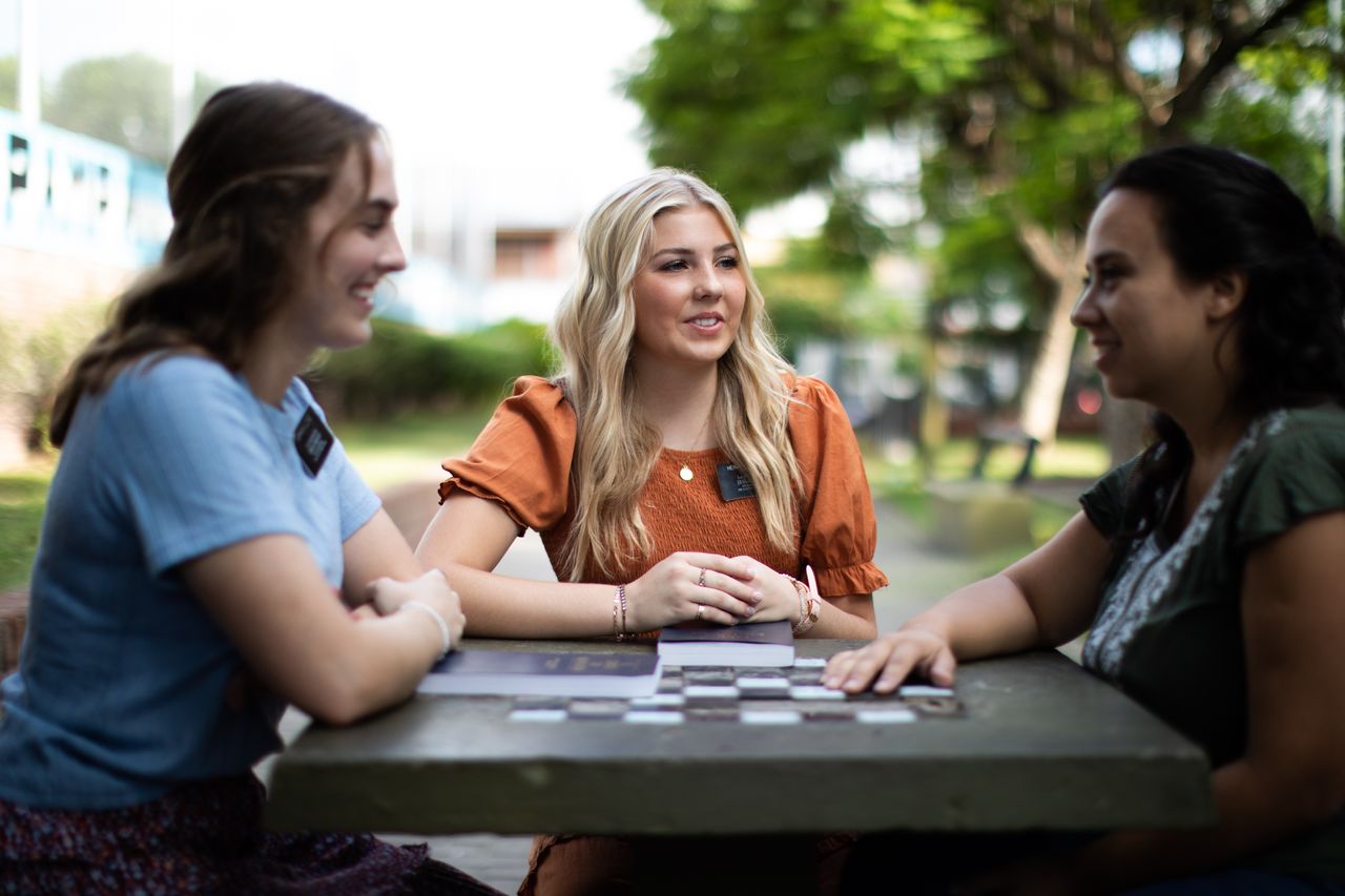 Missionnaires instruisant une femme pendant qu’ils sont assis dehors à une table