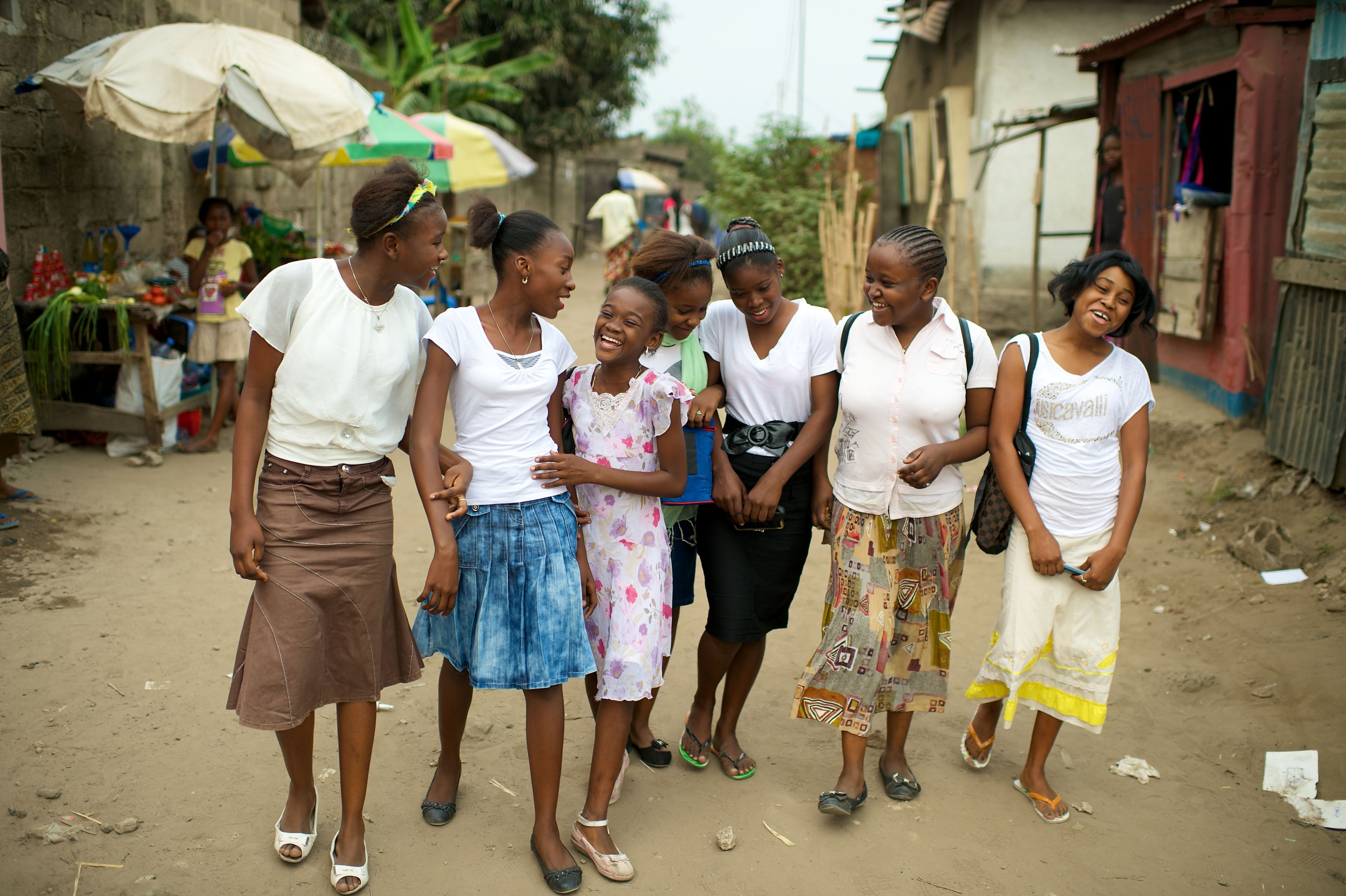 A group of young women walking in a row down a street in Africa.