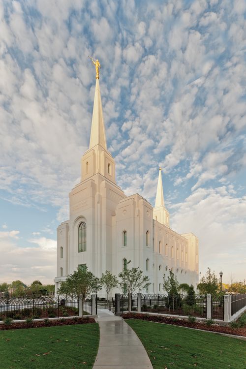 The Brigham City Utah Temple on a sunny day, with small white clouds in the sky.