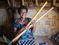 Woman in Vanuatu holding garden tools while sitting in her home page.