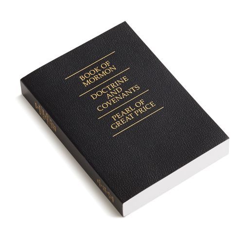 A photograph of a black softcover triple combination with gold text.