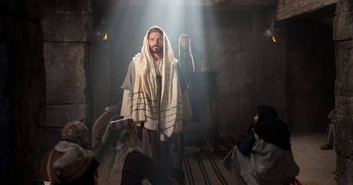 Jesus standing in a synagogue among a seated group, with a shaft of light shining on him. Outtakes include just Jesus, Jesus standing at a pulpit, and Jesus standing away from the pulpit.