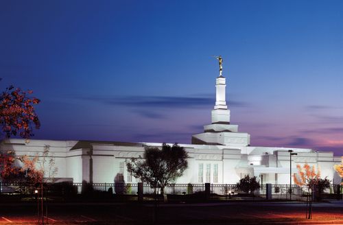 The Fresno California Temple lit up against the evening sky.