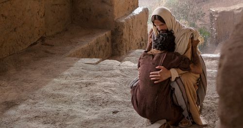 Sabata dienā dziedināto vīru apskauj viņa vecāki, fonā var redzēt Jēzu. Viņš bija neredzīgs kopš dzimšanas. Attēli ietver dziedināto vīru, kas apskāvis Jēzus kājas, un viņa vecākus. blind-man-healed-parents-rejoice