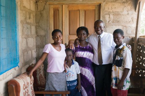 A mother and father stand and smile with their three children.