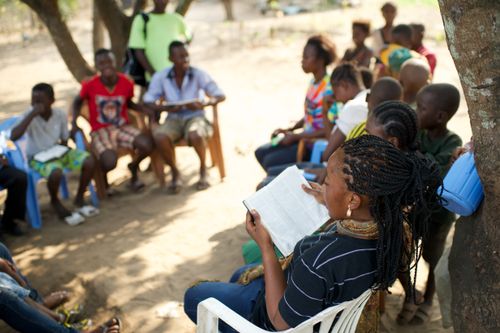 Members in the Democratic Republic of the Congo sitting together outside, studying scriptures.