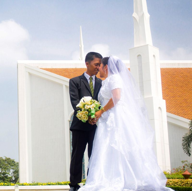 A bride and groom in front of the Manila Philippines Temple.