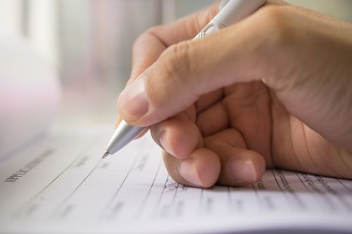 close-up of person filling out paperwork