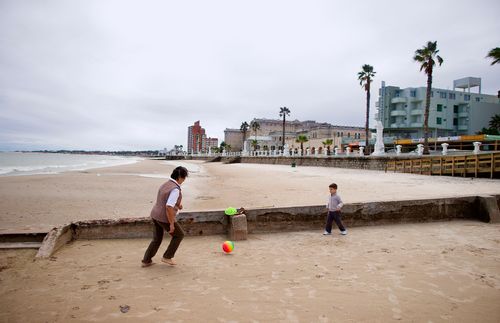 해변가에서 남자아이와 공을 차는 여성.