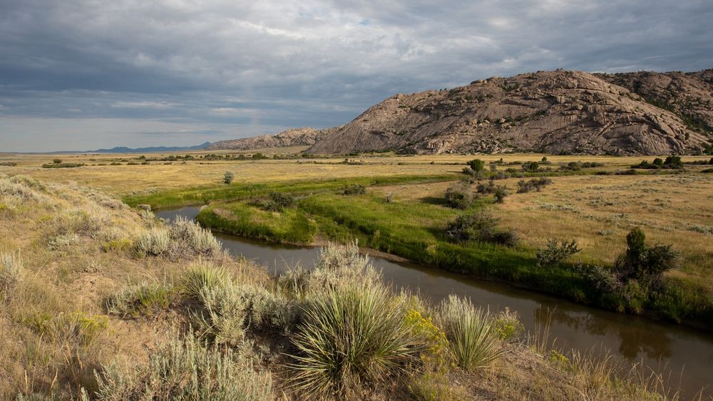 Prairie landscape of Martin's Cove in Wyoming, with Sweetwater River, hills, and clouds. (horiz)