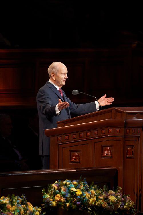President Russell M. Nelson standing at the pulpit with his arms extended, speaking in general conference in April 2018.