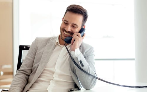 Man in suit using a desk phone