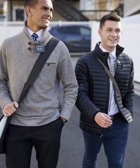 A missionary models appropriate jackets and suits and he smiles and walks with his companion.
