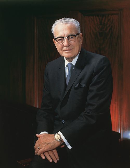 A portrait by Merrett T. Smith of President Harold B. Lee wearing a white shirt, black suit, and glasses.