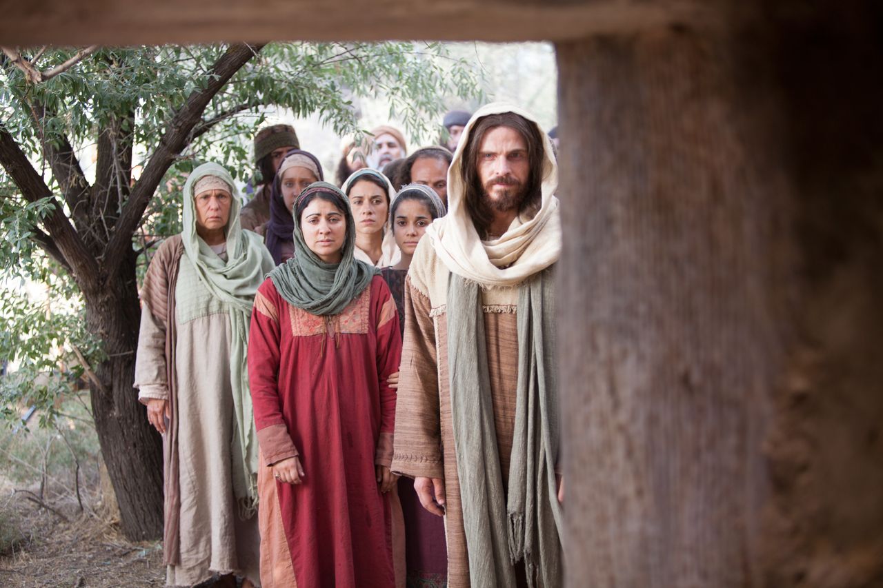 Christ approaches a tomb with a multitude of people behind Him