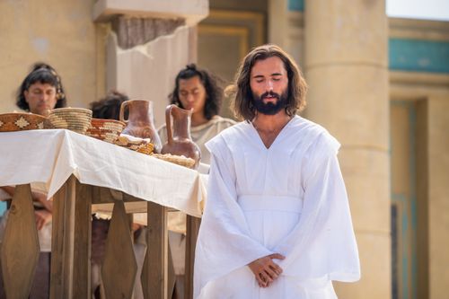 Jesus Christ hands the sacrament bread and wine to the Nephites.