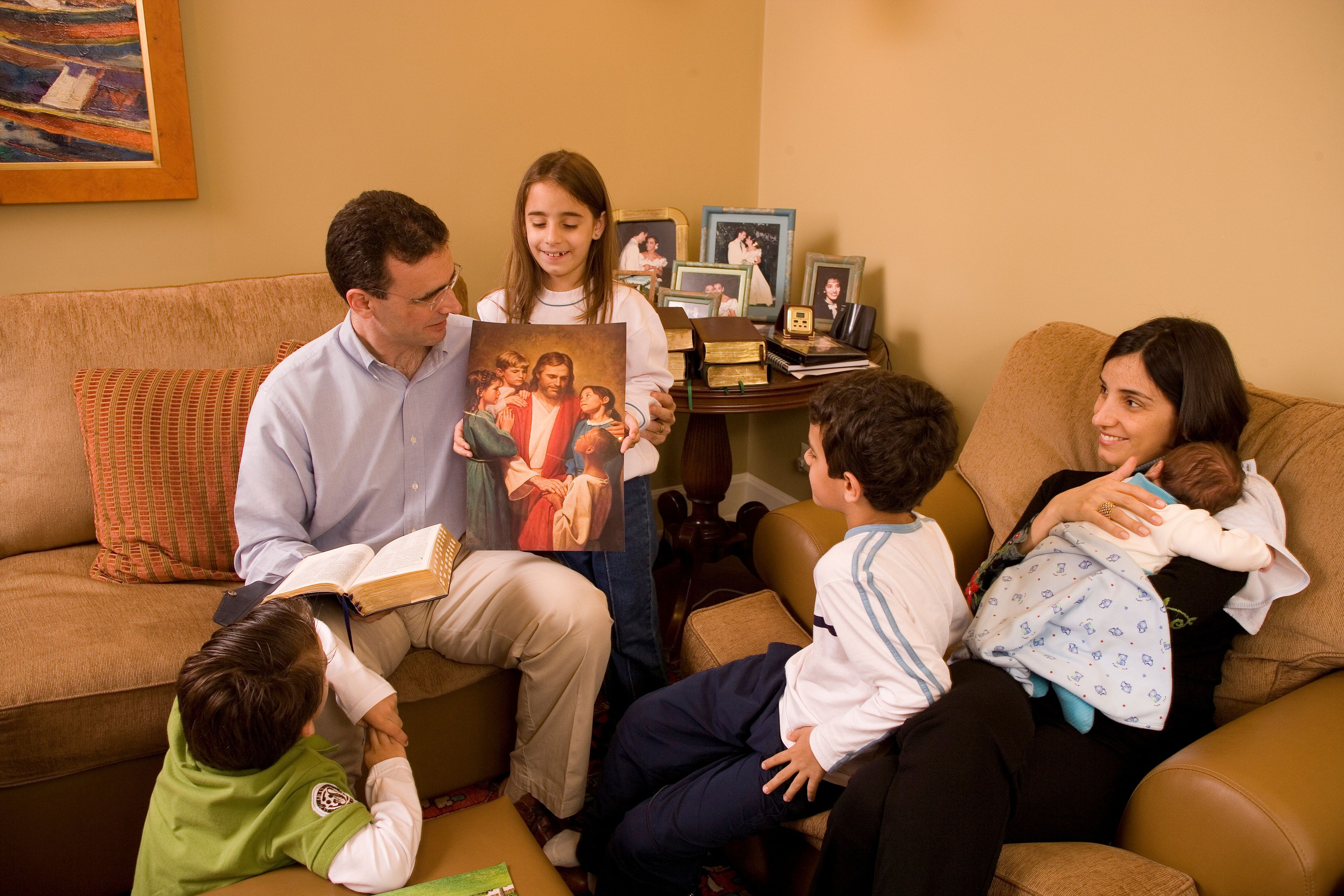 A family of six looking at an image of Christ with children during family home evening.