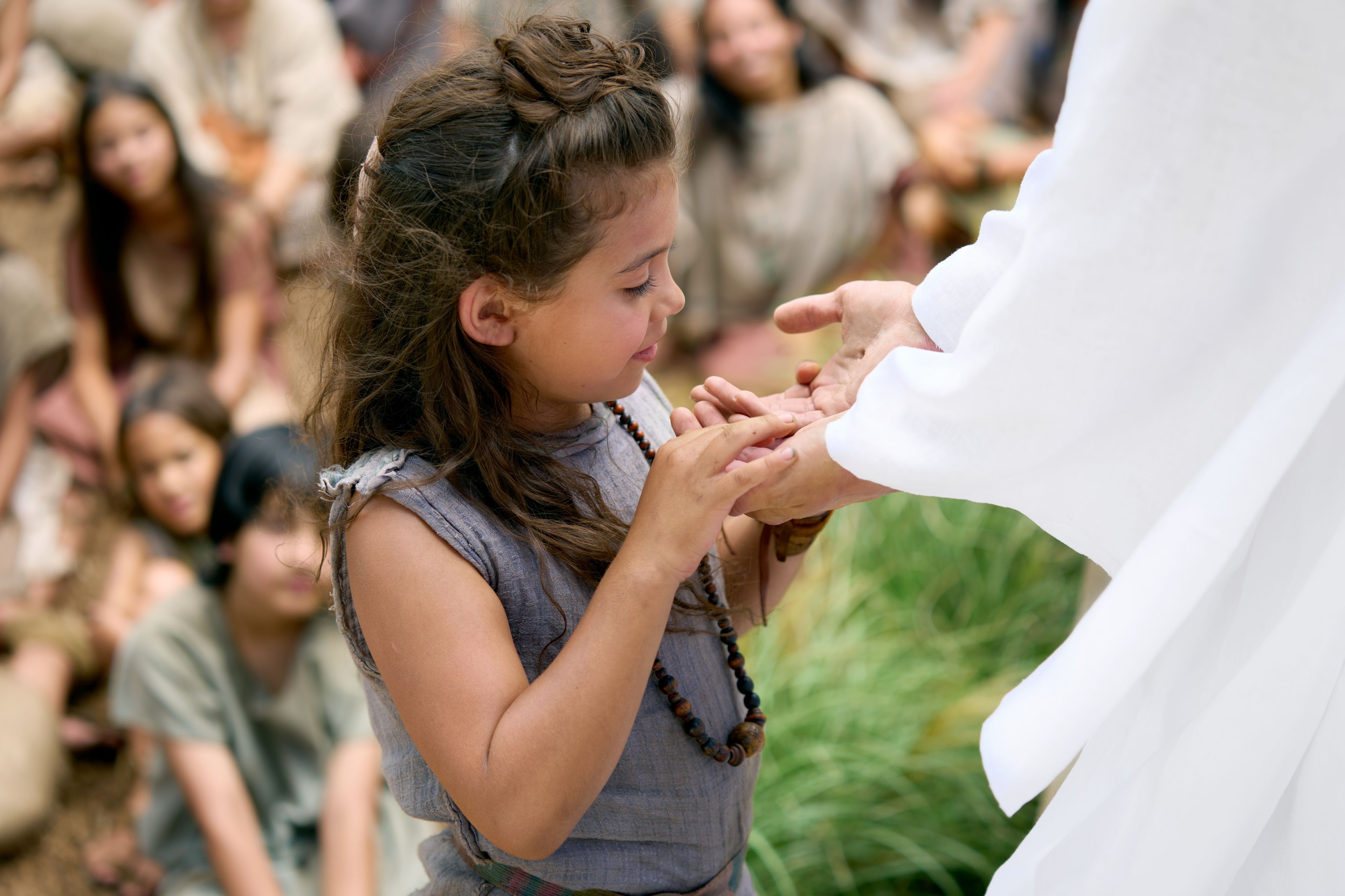 A young girl looks at the marks of the nails in the resurrected Savior, Jesus Christ's, hands.