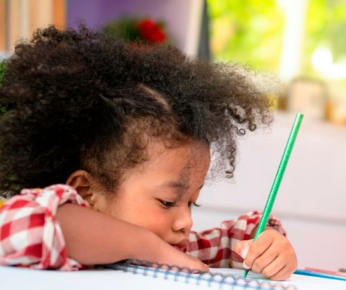 Young girl coloring in notebook