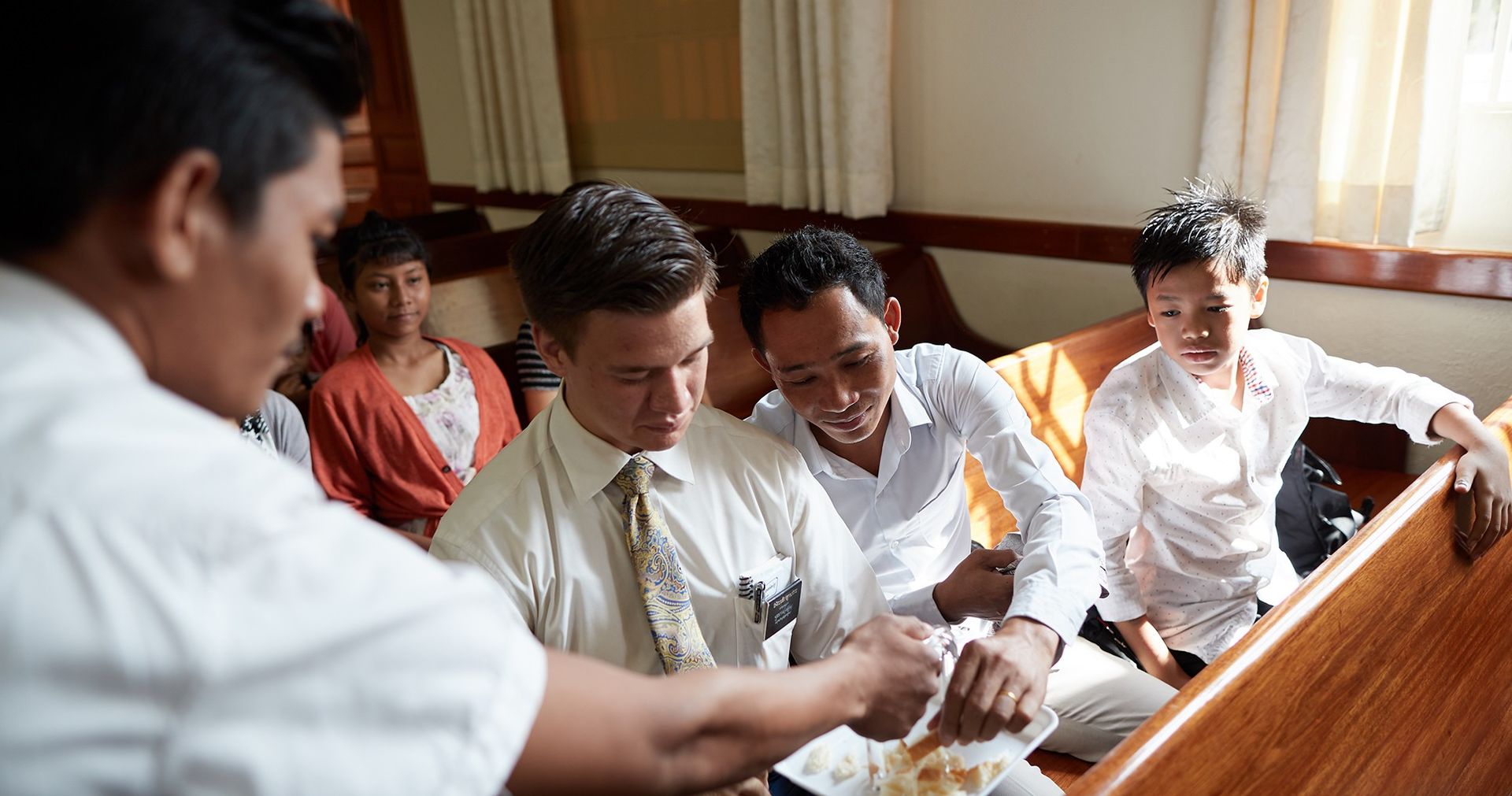 Young men pass the sacrament during a church service in Takmau, Cambodia. 