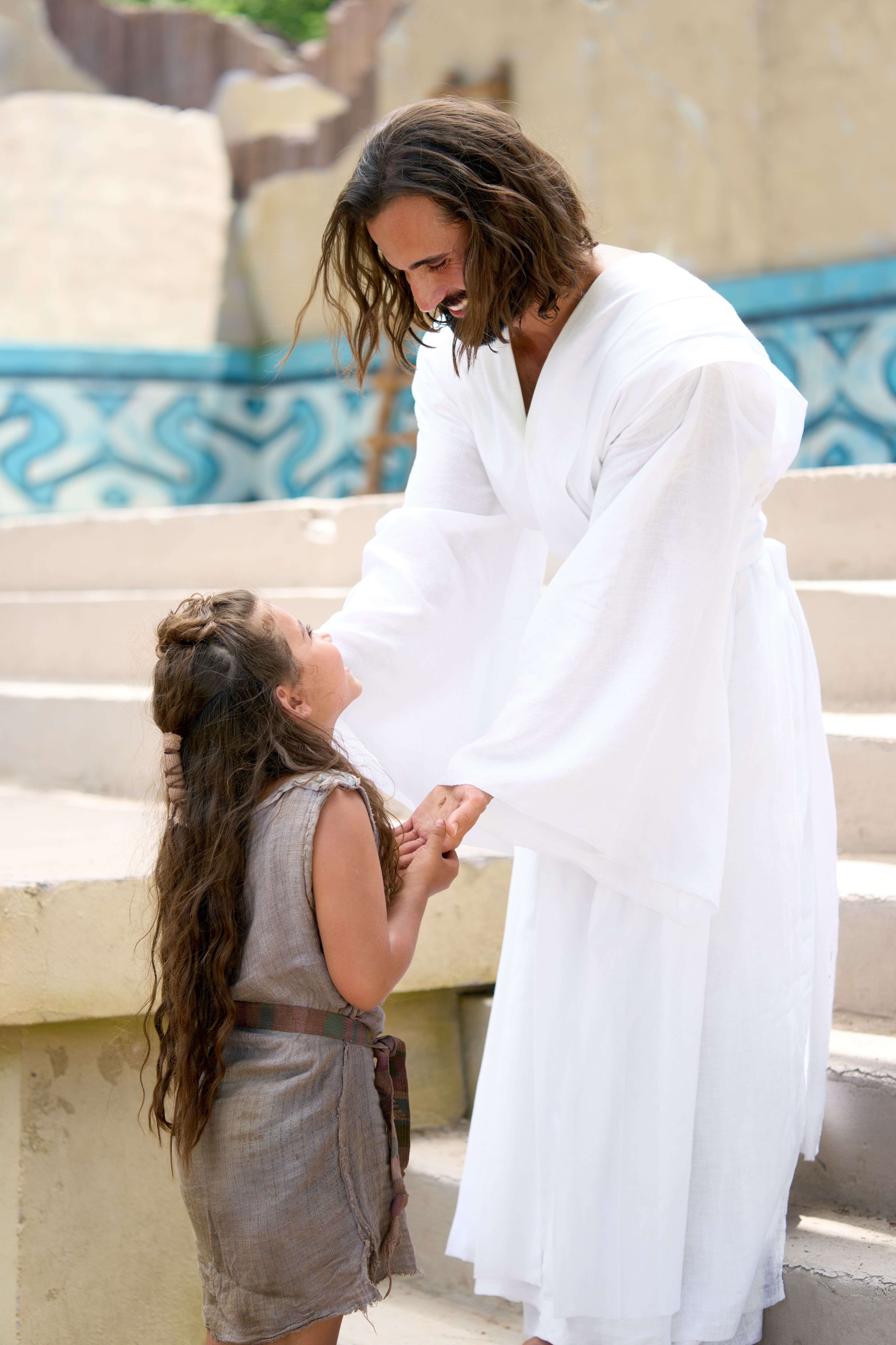The resurrected Savior, Jesus Christ smiles as he ministers to a young girl during his visit with the ancient inhabitants of America.