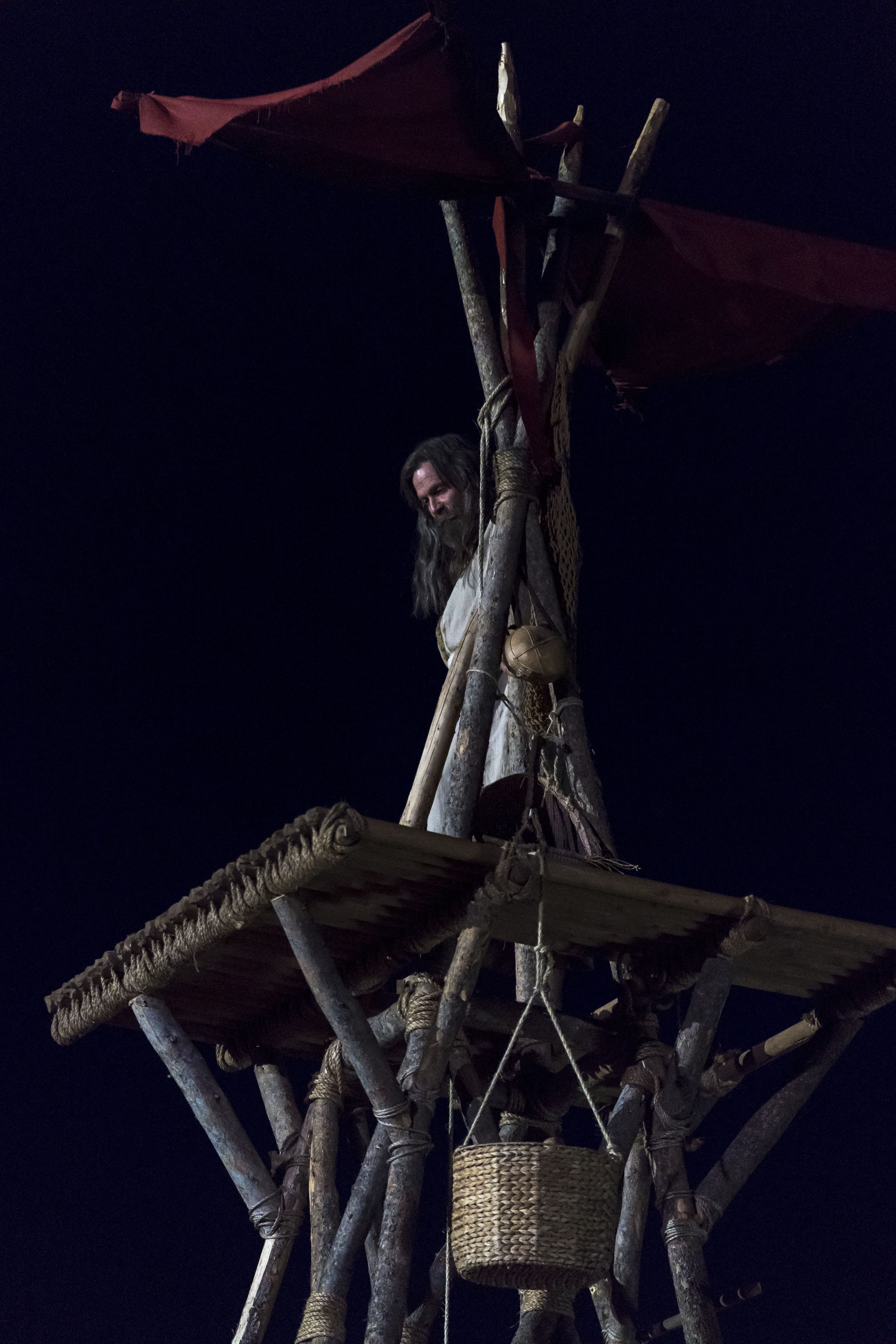 Older Jacob standing on the top of a tower at night. 