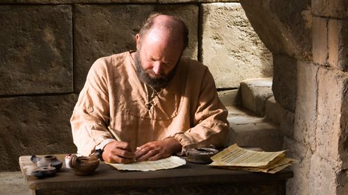 Pablo sentado en un escritorio, escribiendo