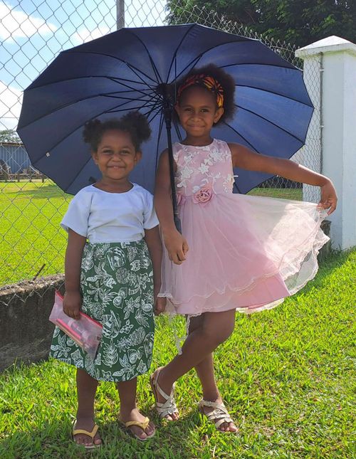 Emma and her sister under an umbrella
