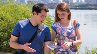 Men and women sharing the book of Mormon with another person as they walk.
