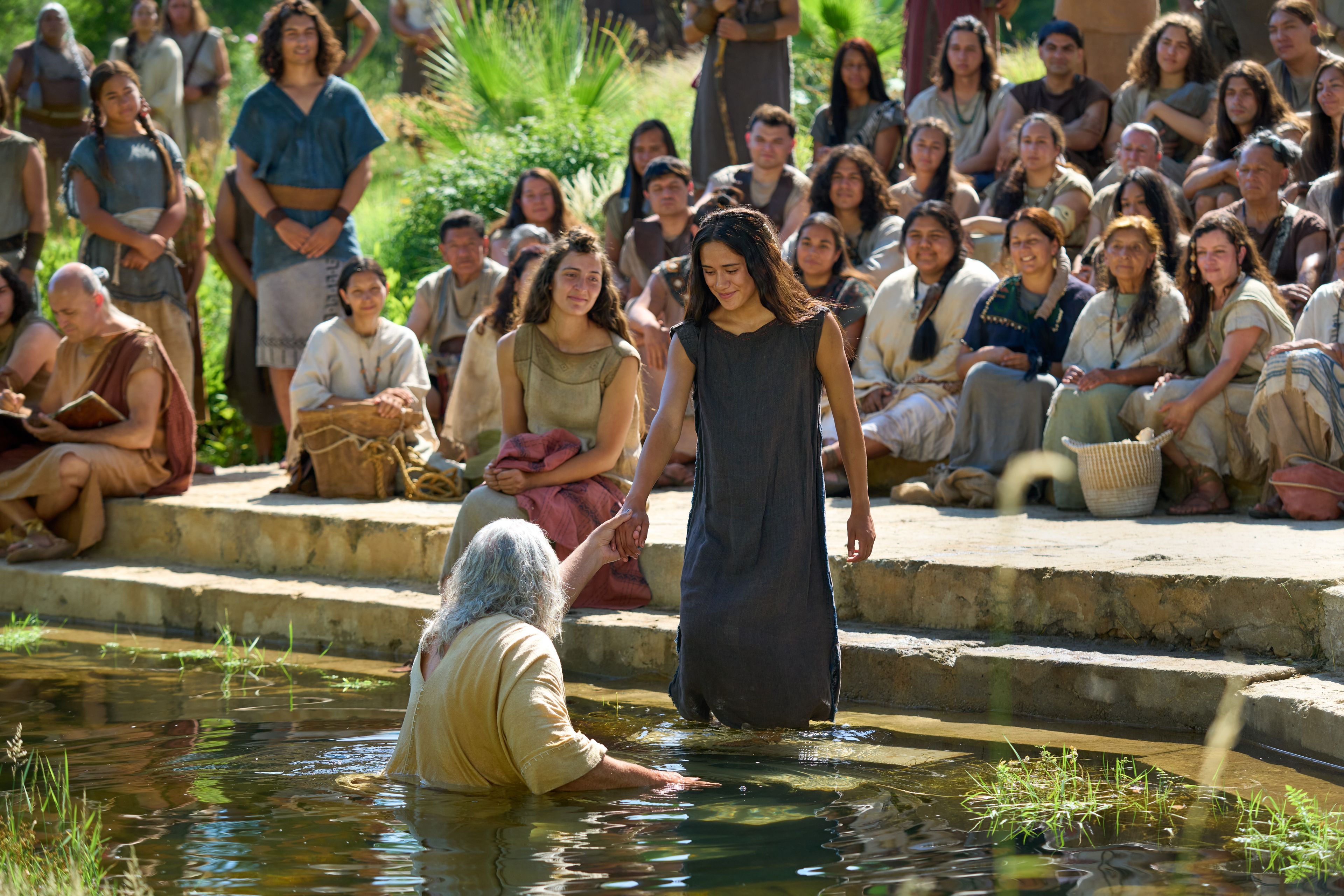 Nephi helps a woman walk down into the water to be baptized. He had previously been set apart and given the authority by the resurrected Savior, Jesus Christ.