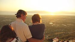 Foto de una pareja y una hija mirando un valle desde una colina