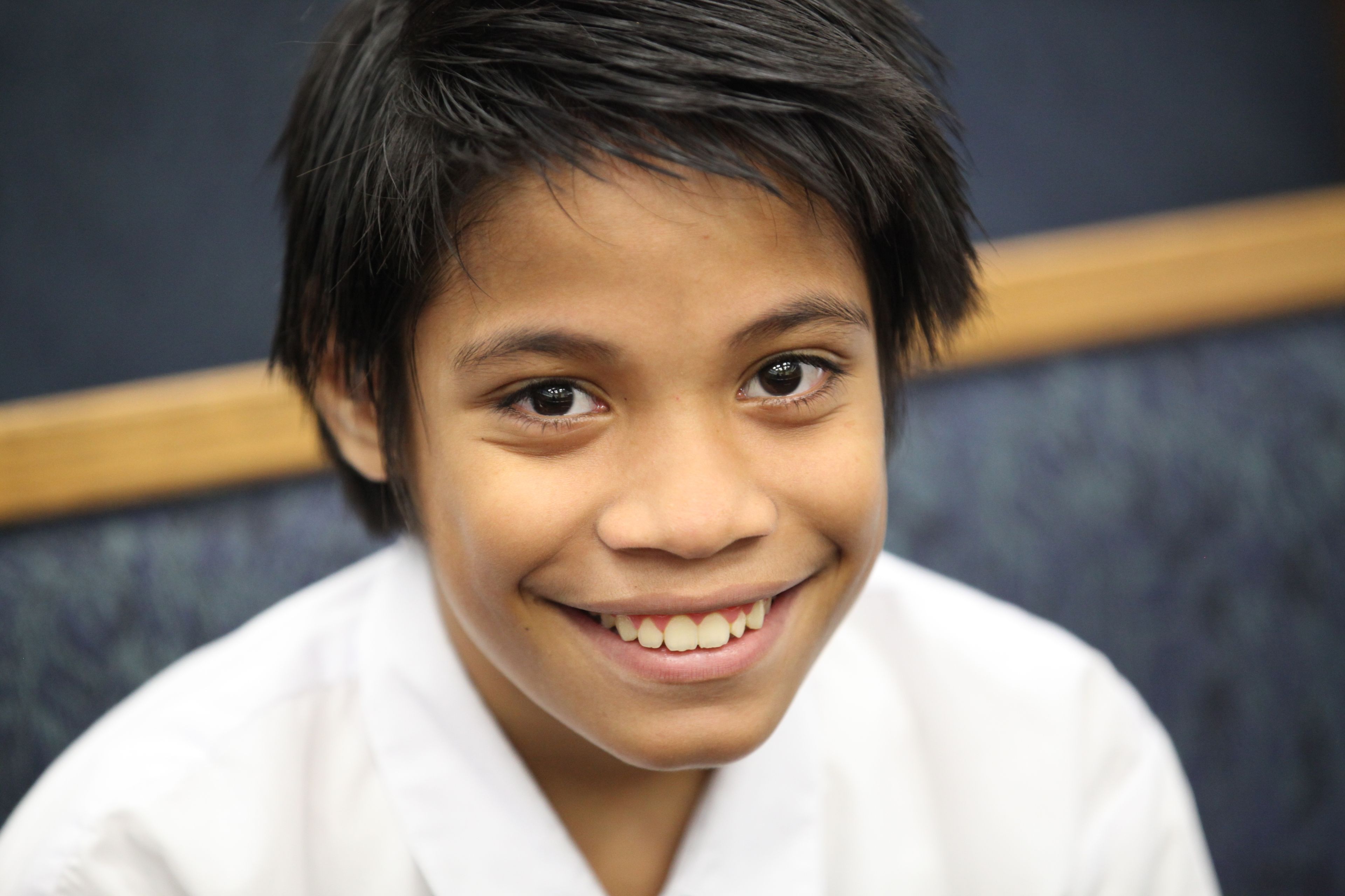 A young boy smiling dressed in church clothes.