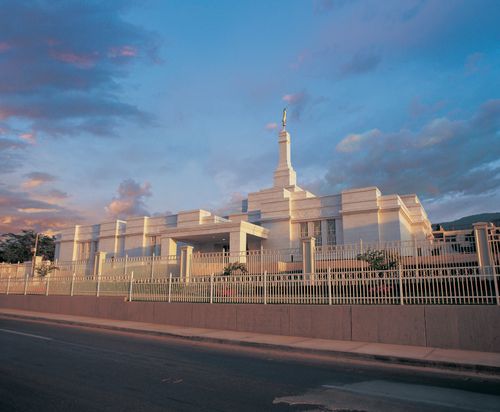 The Tuxtla Gutiérrez Mexico Temple behind two white fences, with a partly cloudy sky overhead.