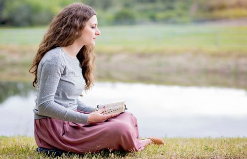 Eine junge Frau hält die heiligen Schriften in den Händen und schaut in die Ferne