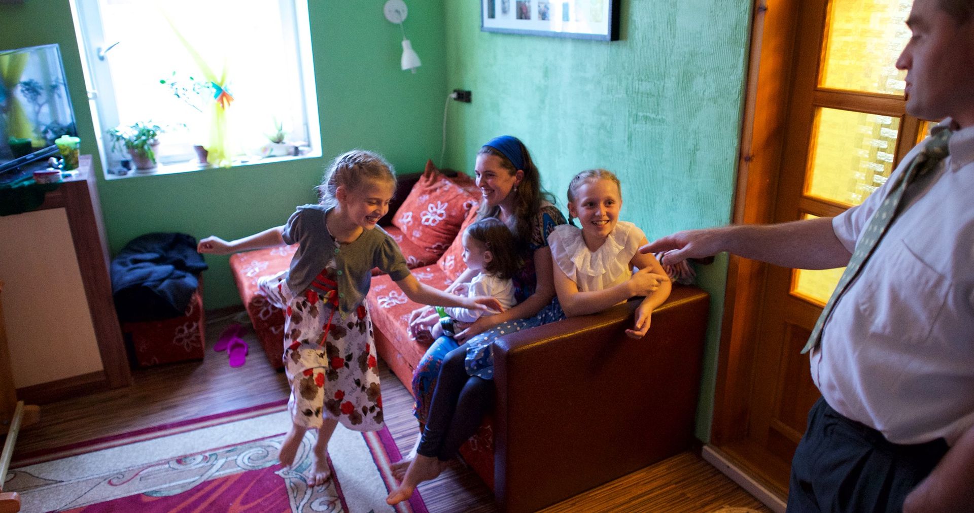 A young Latvian couple with three little girls smiling and playing together.