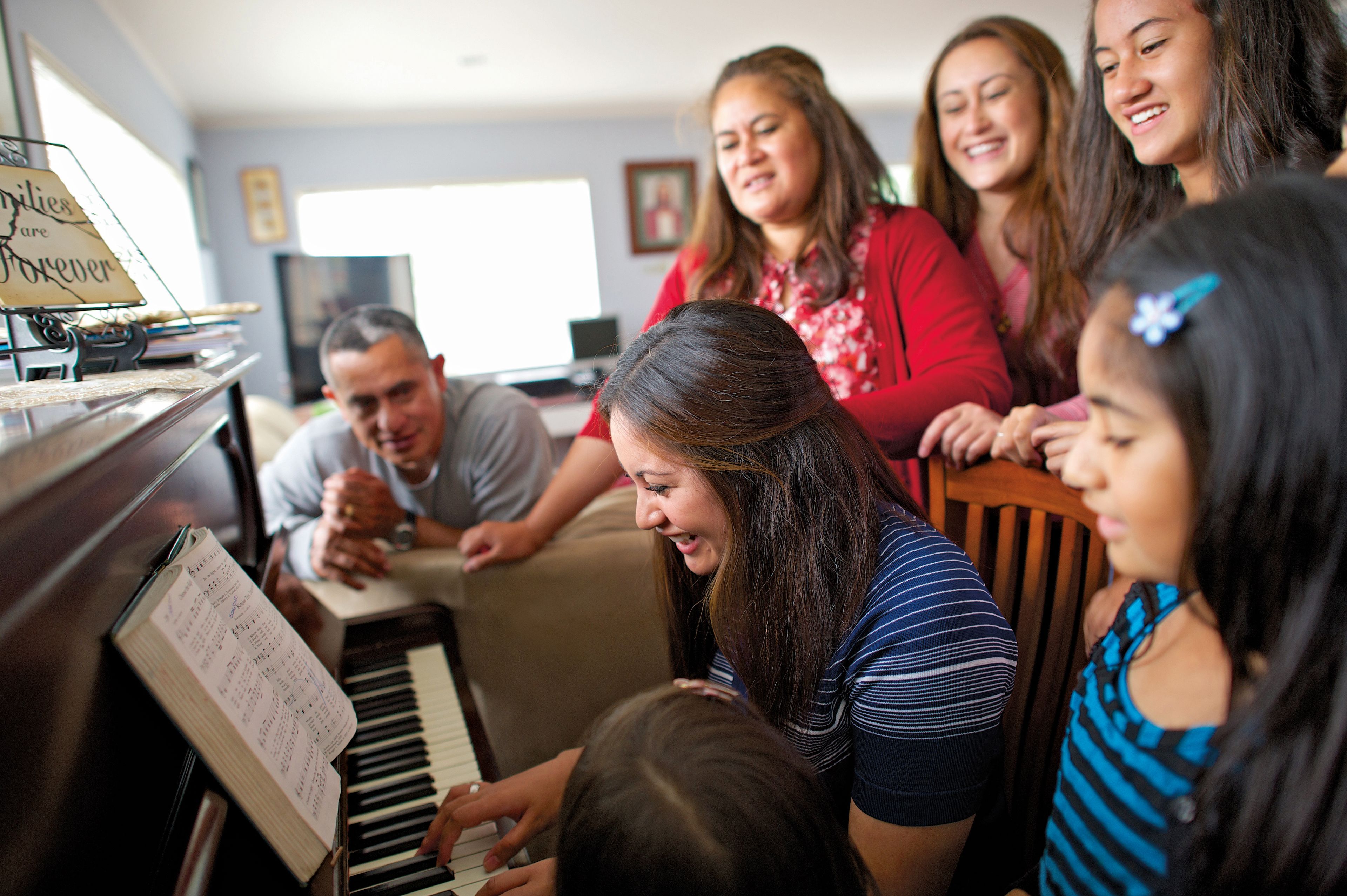 A family gathers around the piano and sings together as a daughter plays.