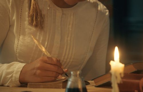 woman writing in journal by candlelight