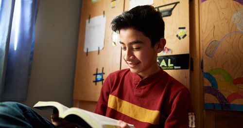 A teenage boy is in his bedroom. He is reading and studying the scriptures. This is in El Paso, Texas.