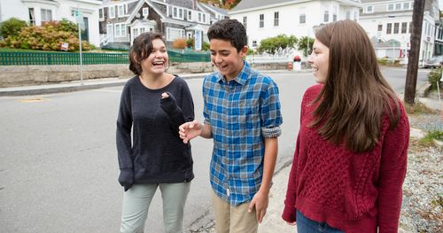 A group of teenagers walk together in the city. They appear to be friends and are talking with one another. This is in Maine.