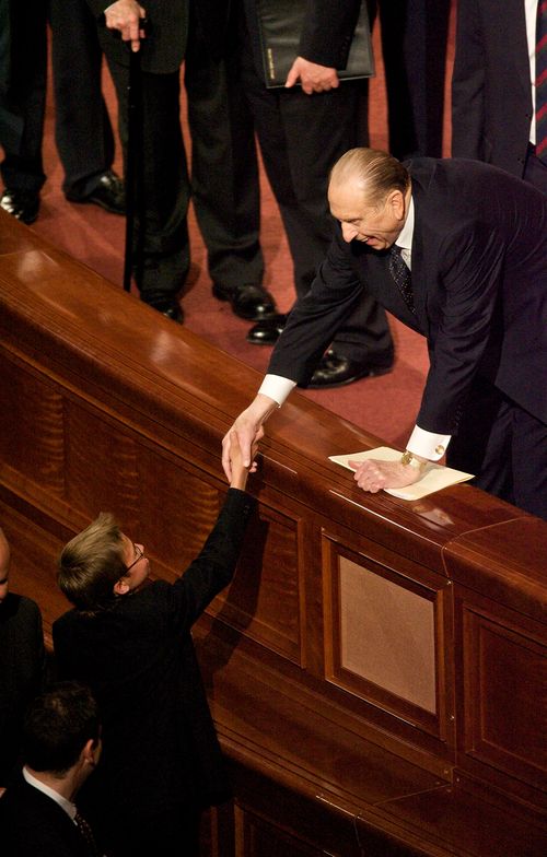 Президент Монсон протягивает руку юноше для рукопожатия