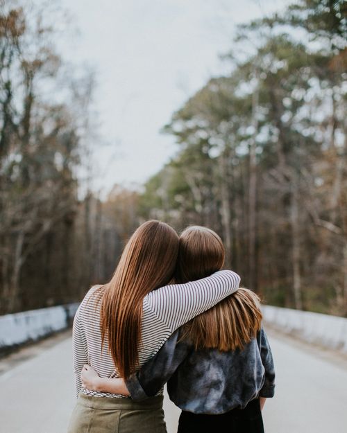 two girls embracing each other while looking down road