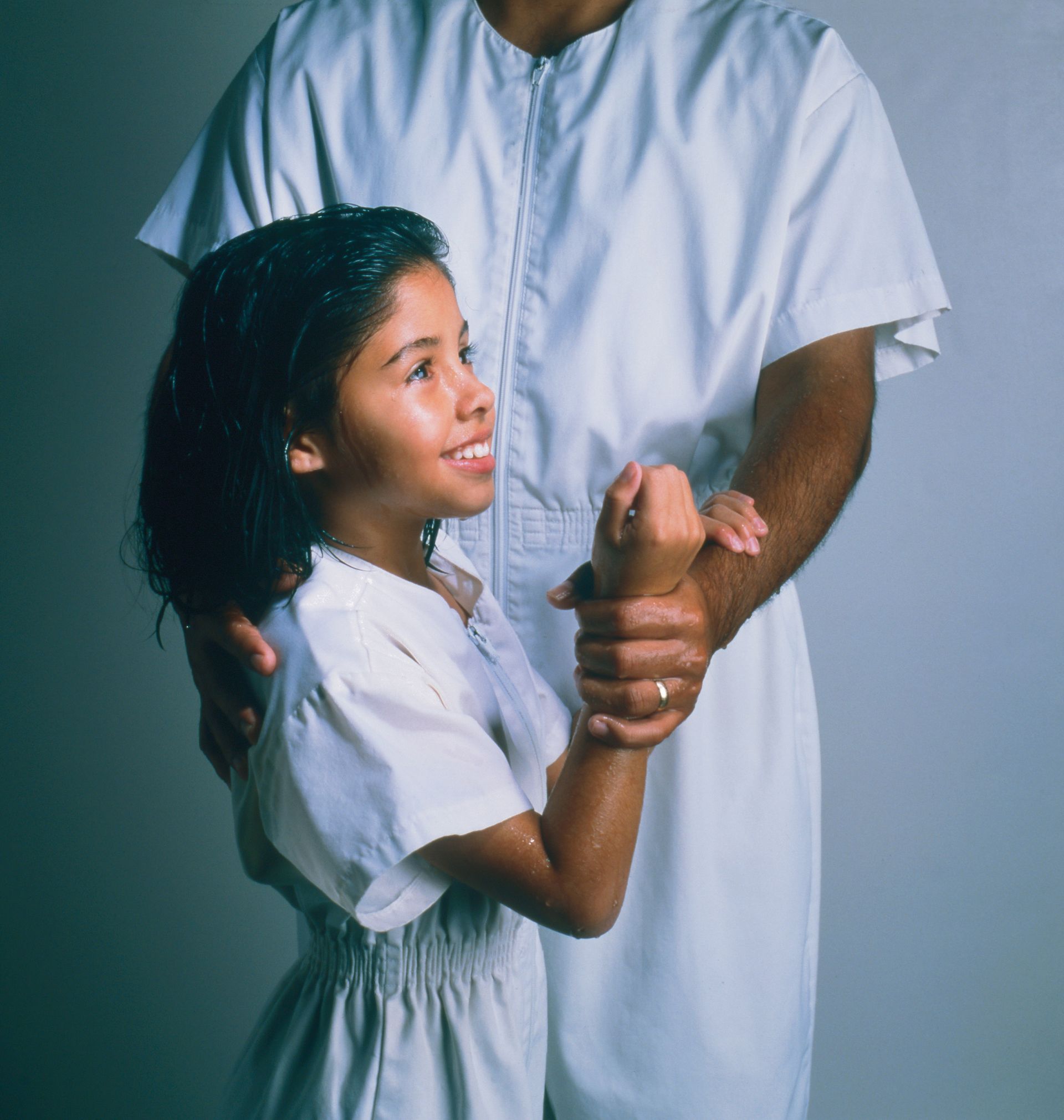 An eight-year-old girl and a priesthood holder standing together, in position for baptism.
