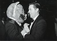 At his Inauguration celebrations, Jeffrey R. Holland clasps hands with Cosmo the Cougar (BYU Mascot), 1980.